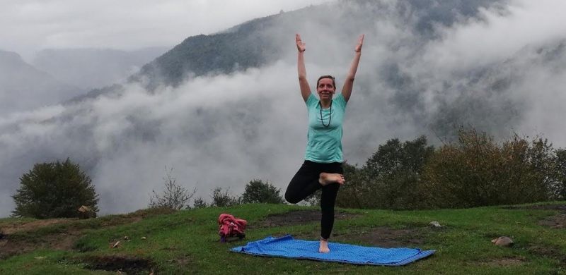 A woman practicing the Tree Pose yoga in nature among misty mountains, symbolizing peace and balance between mind and body.