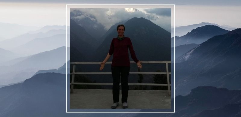 A woman standing with a smile in a mountain landscape, a symbol of balance, calm, and body stability